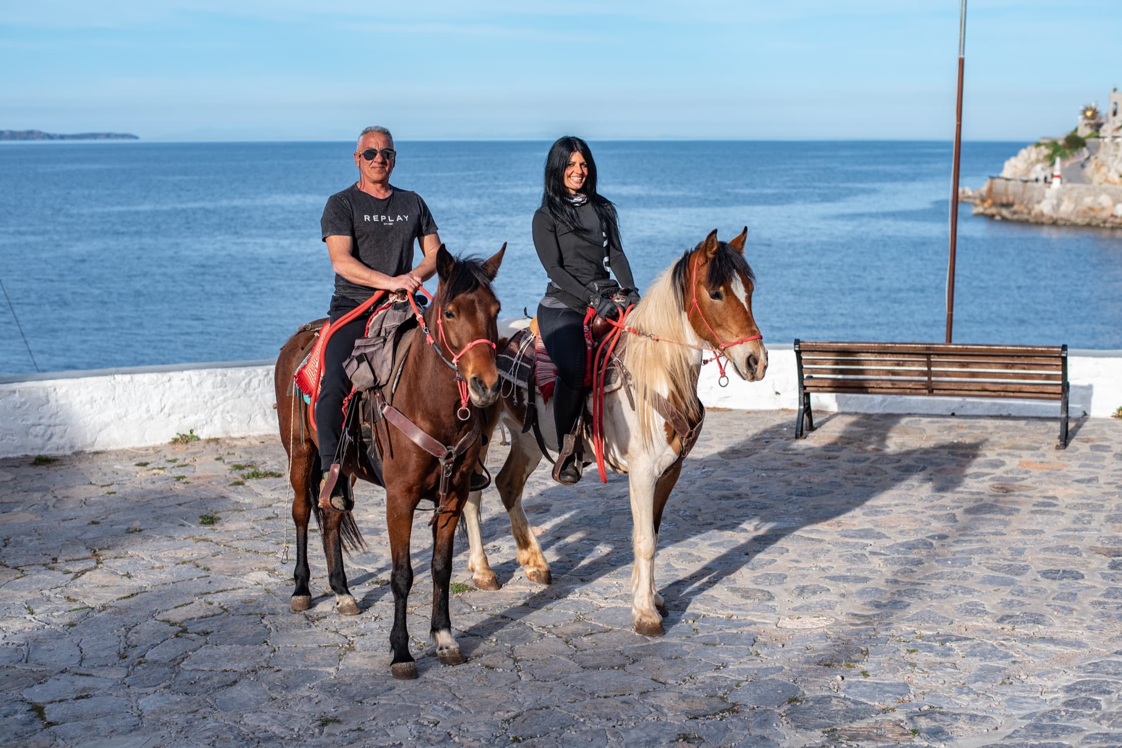 Two riders pause by the sea on Hydra