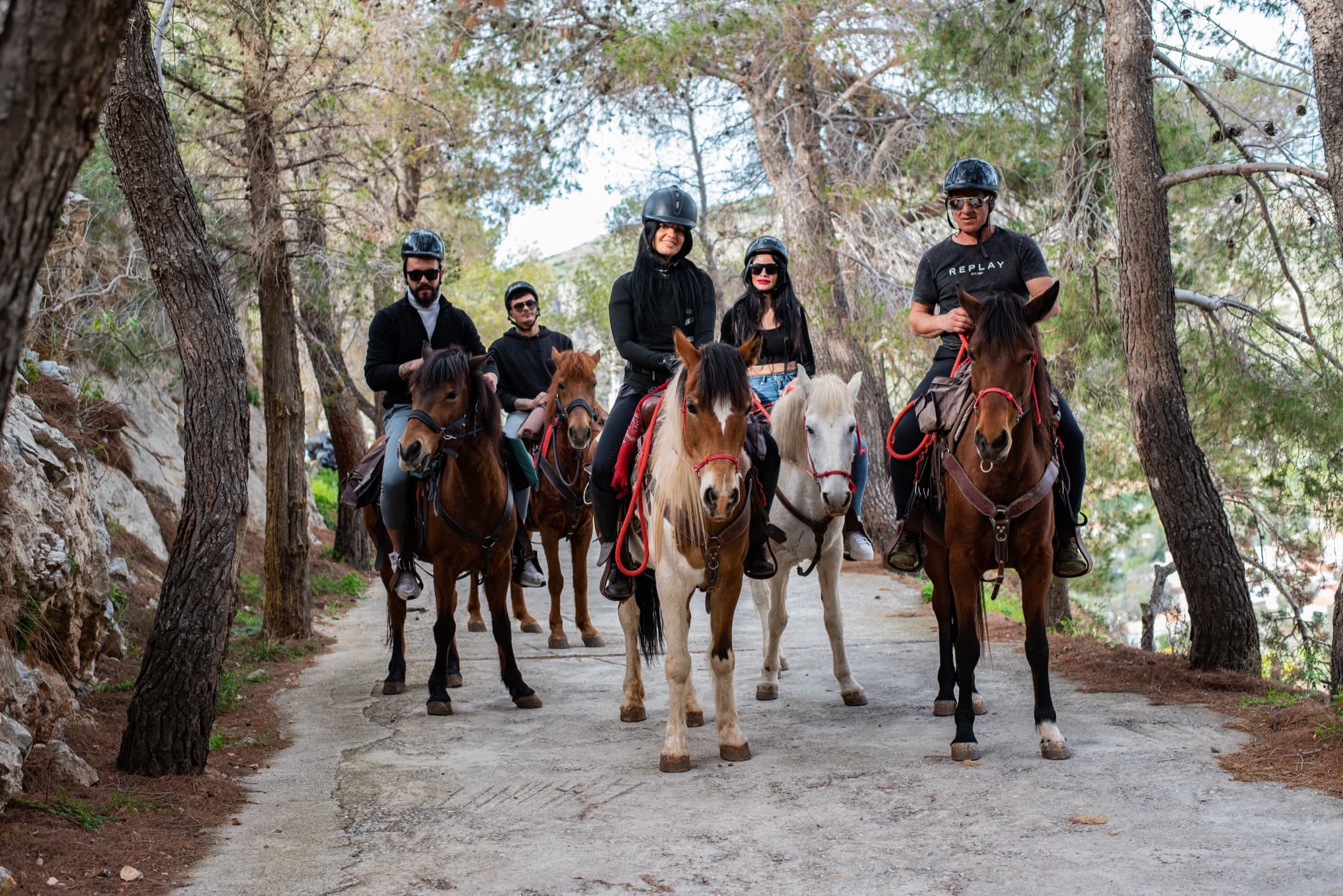 A group of riders smiling on a wooded trail
